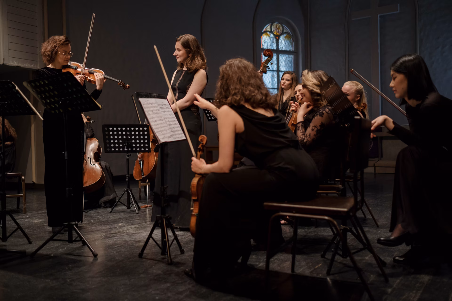 Symphony orchestra rehearsing together on a dimly lit stage