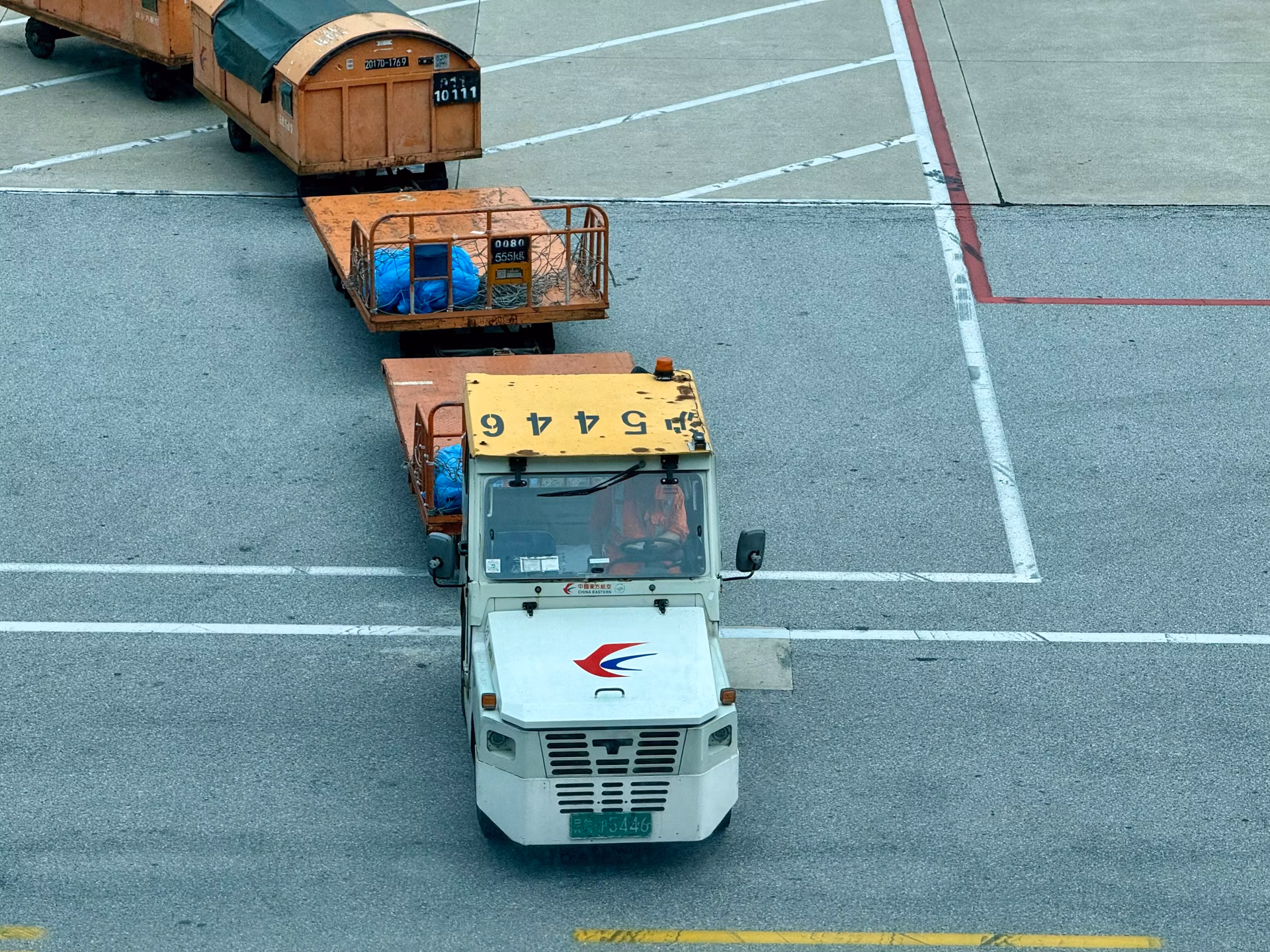 Airport tow tractor moving unbranded freight containers across the tarmac
